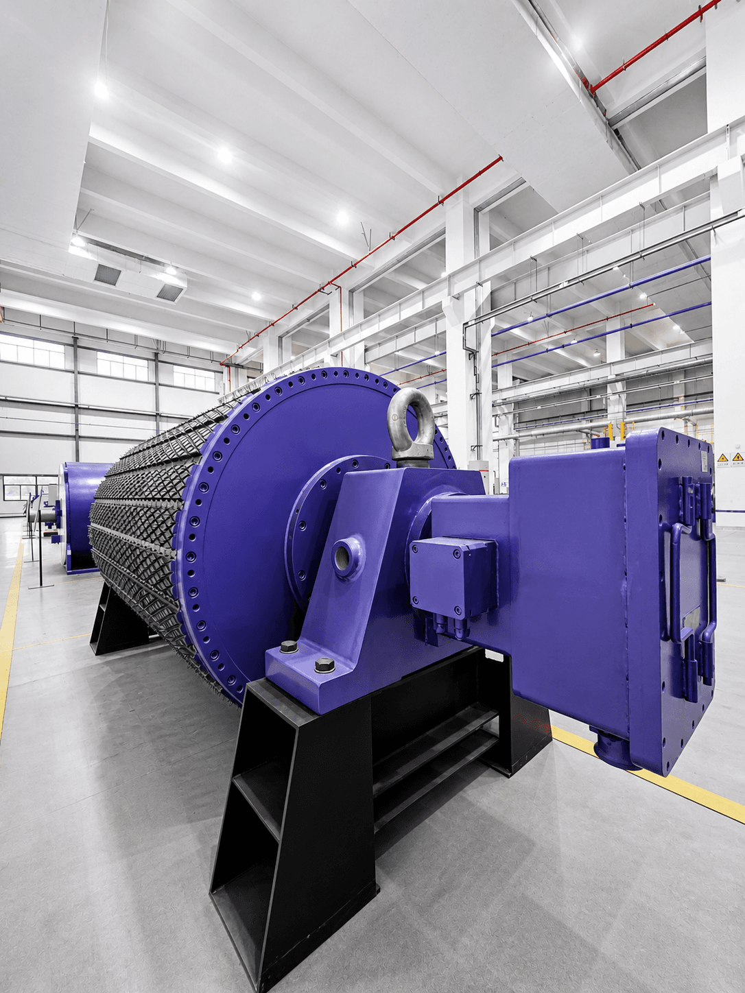 Large purple industrial drum machine on a black stand in a bright factory setting.
