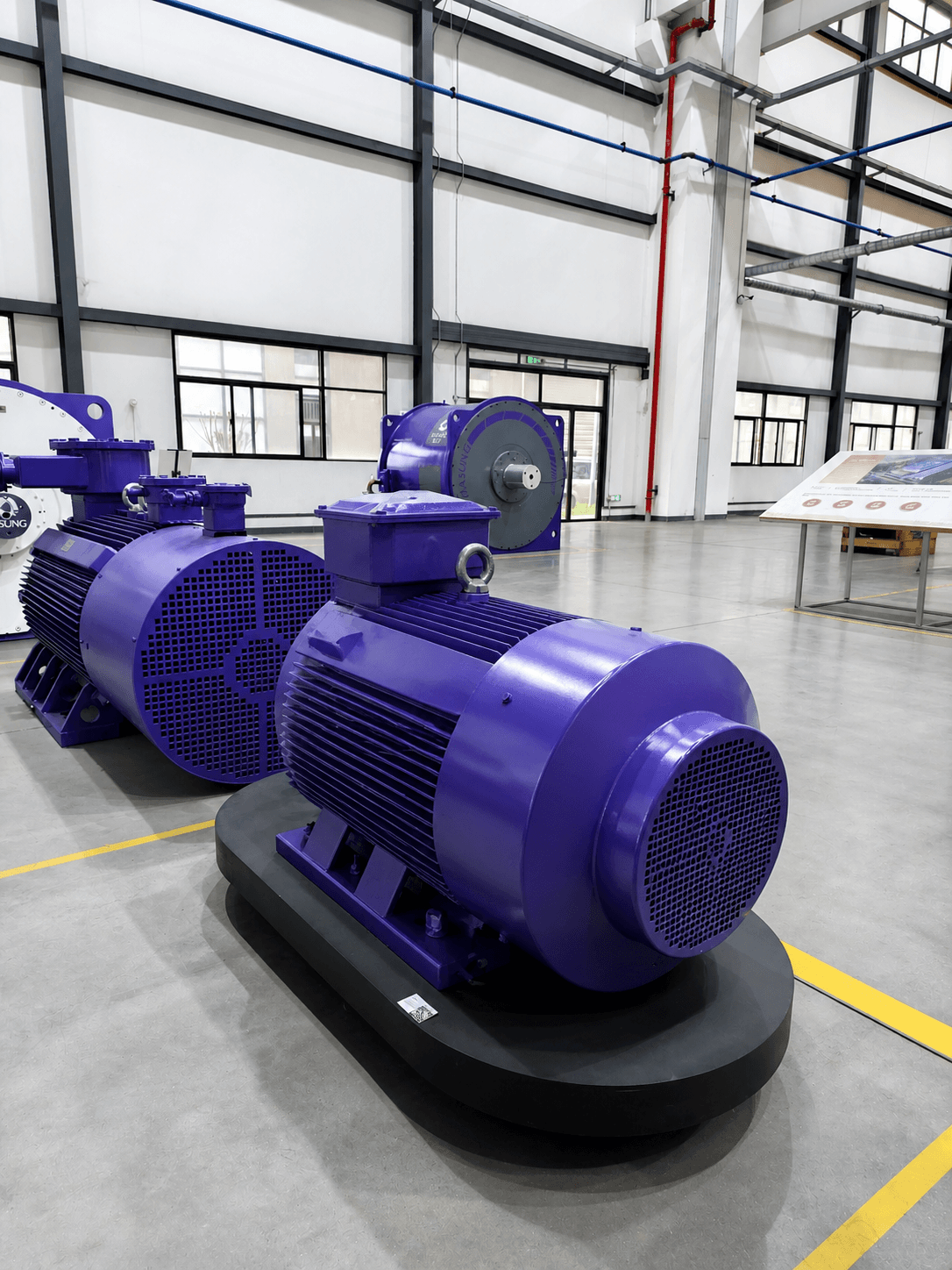 Large purple industrial electric motors on black bases inside a bright, modern factory.
