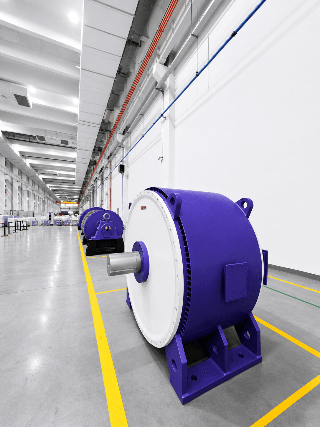 Large purple industrial motors lined up in a bright, modern factory with yellow floor markings.